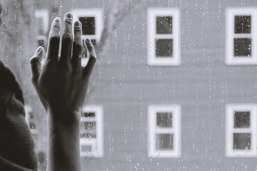 a hand resting on a window glass