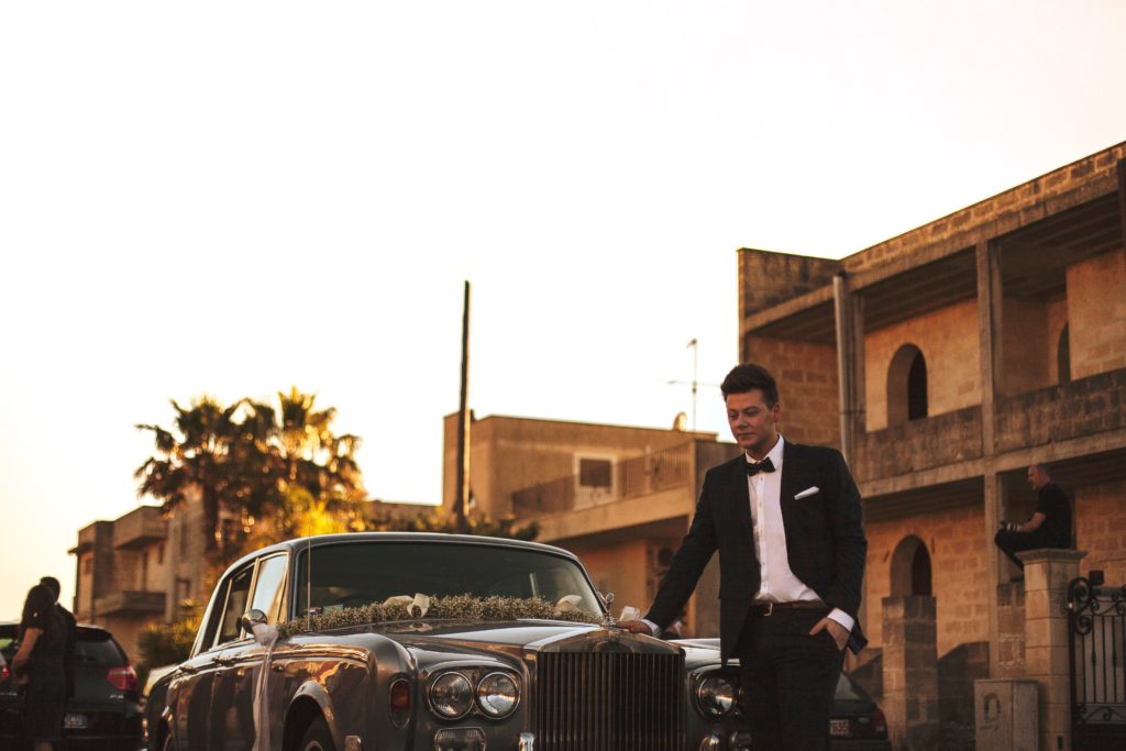 Man in tuxedo waiting near car