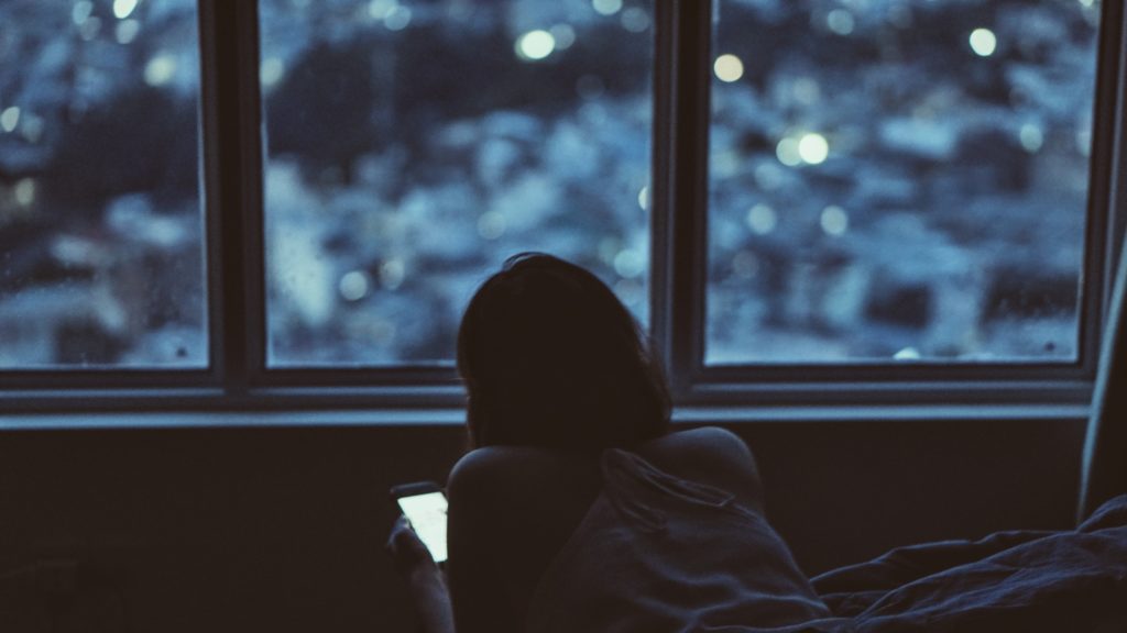 woman looking at phone in front of window